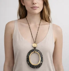 mujer luce un Collar largo con colgante ovalado animal print y aro dorado grande.